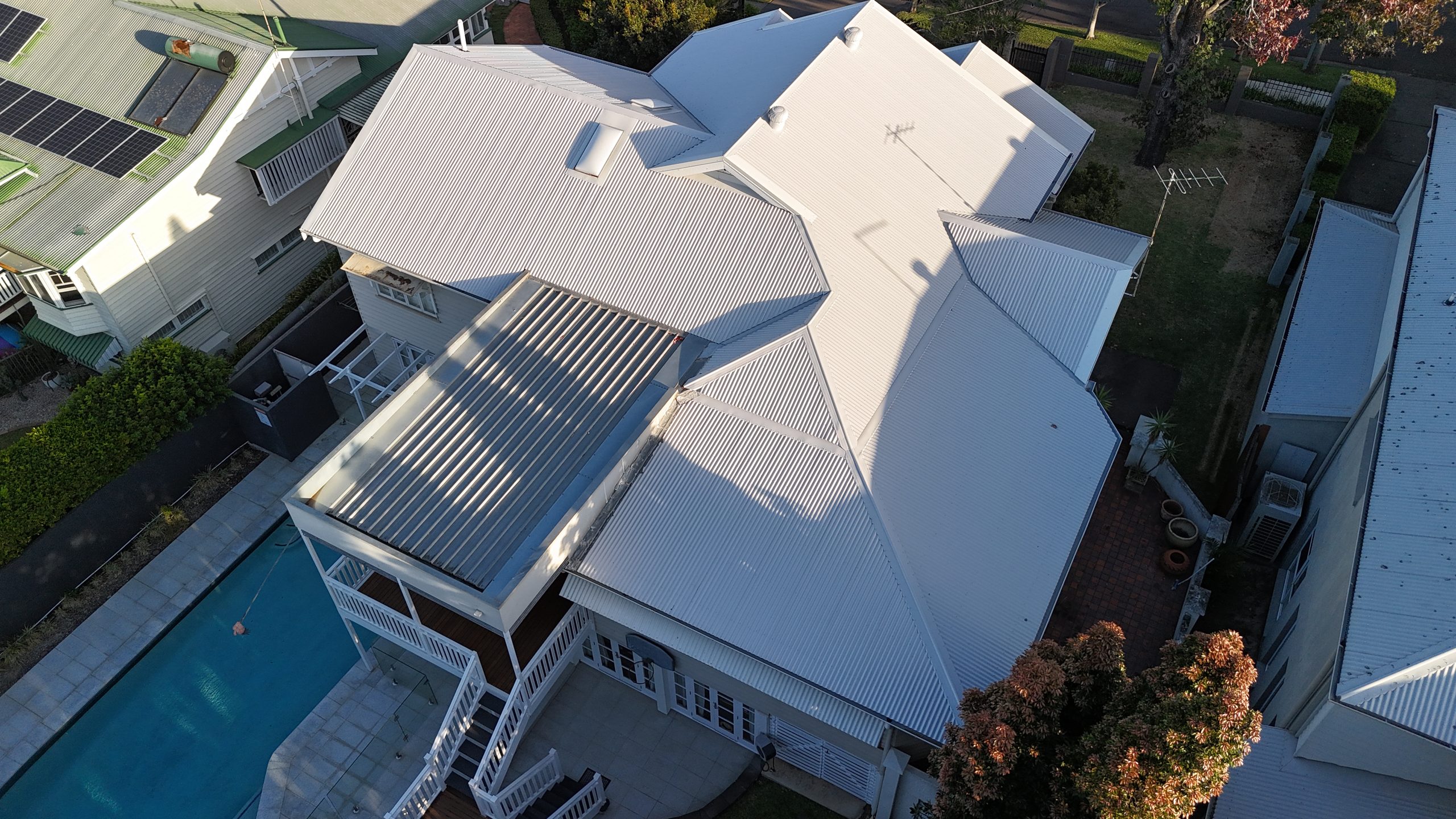 Aerial view of a Queenslander-style home with a freshly installed white corrugated metal roof and pool deck in Ascot, Brisbane.